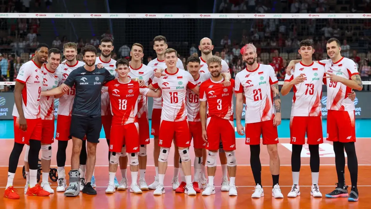 Drużyna siatkarzy Polski w czerwono-białych strojach pozuje do zdjęcia na boisku.